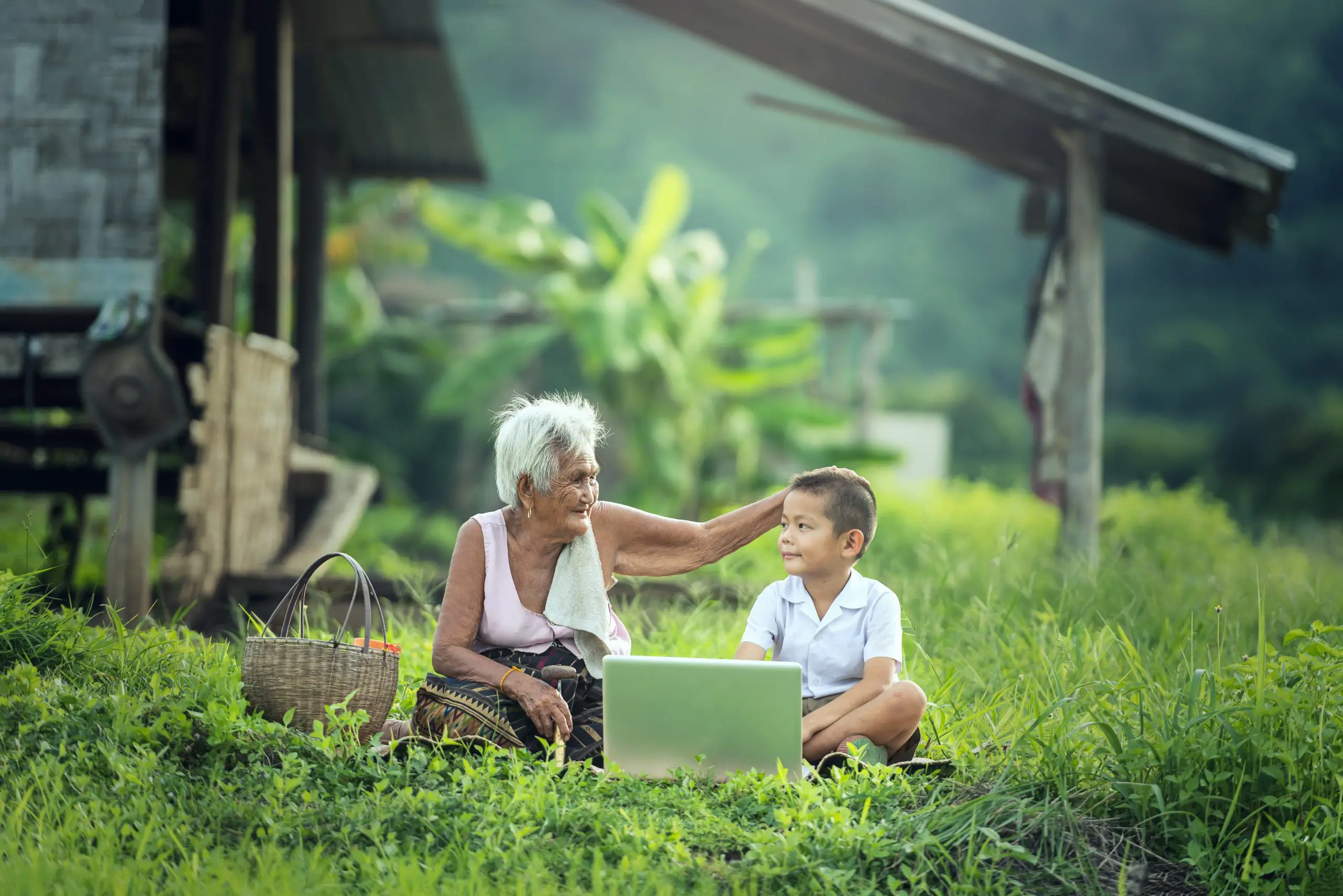 Happy boy and grandmother using a laptop outdoors